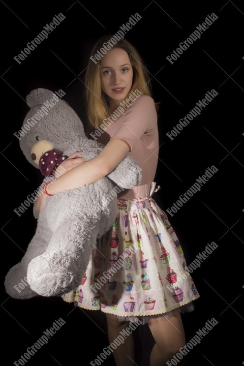 Young girl hugging with her big teddy on black background