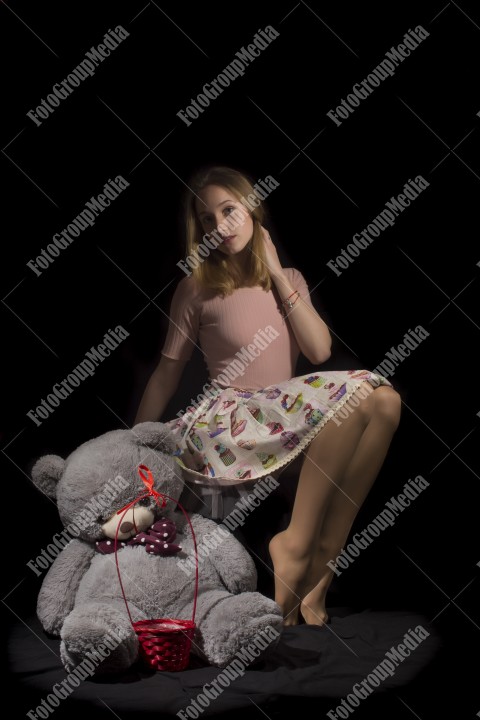 Young girl with big teddy on black background