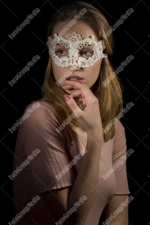 Portrait of a shy girl wearing lace mask on black background