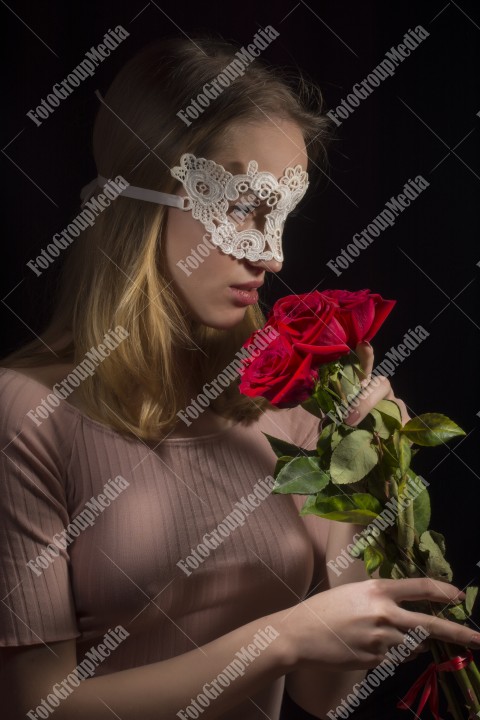 Mysterious attractive woman on black background, with lace mask on face and red roses.