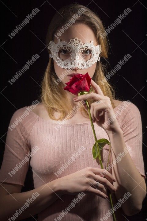 Fashion photo of a girl with a lace mask and rose