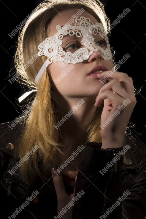 Teenage girl wearing lace mask on black background