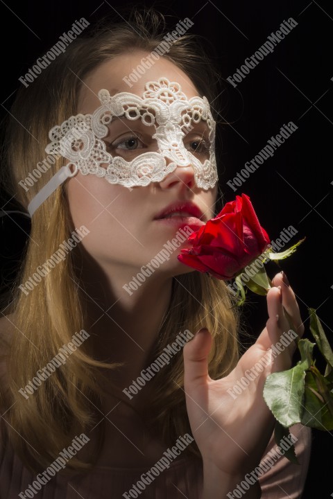 Fashion photo of a girl with a lace mask and rose