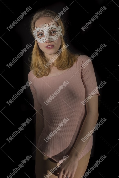 Young attractive woman in mask over black background, lingerie