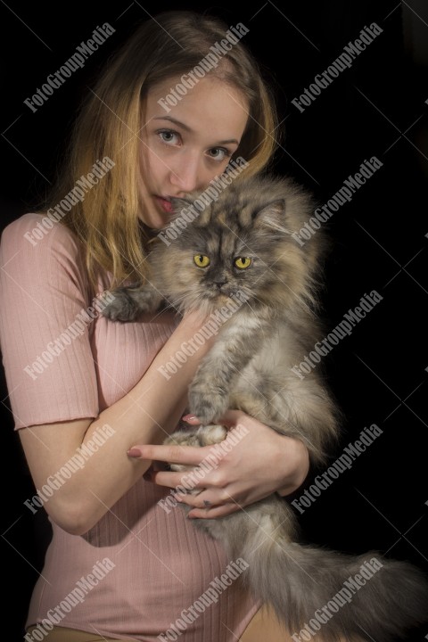 Portrait of young woman with cat on dark background