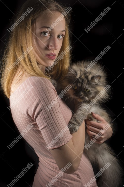 Portrait of young woman with cat on dark background