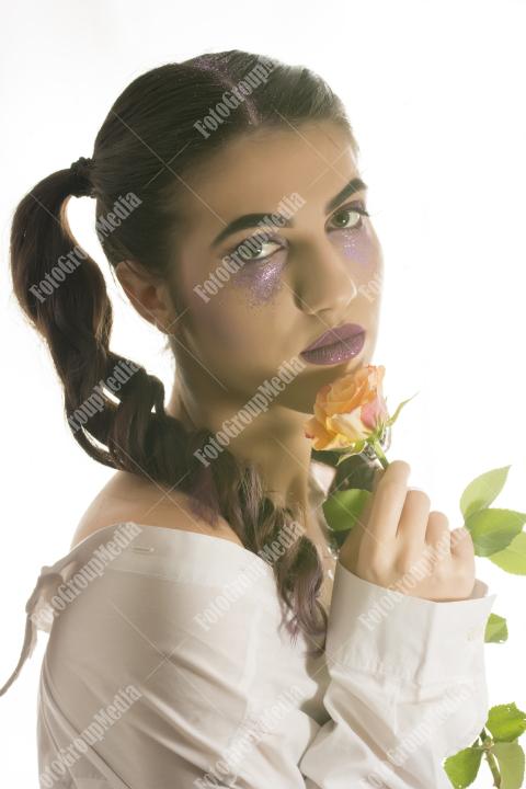 Young girl with artistic make up and yellow rose