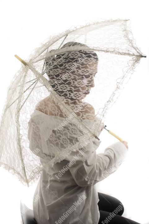 Young girl hiding behind lace umbrella