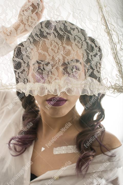 Young girl hiding behind lace umbrella