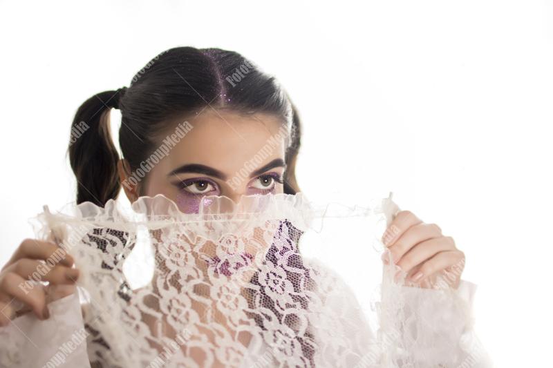 Young girl hiding behind lace umbrella
