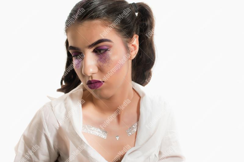 Young girl with two pony tails and artistic make up on white background