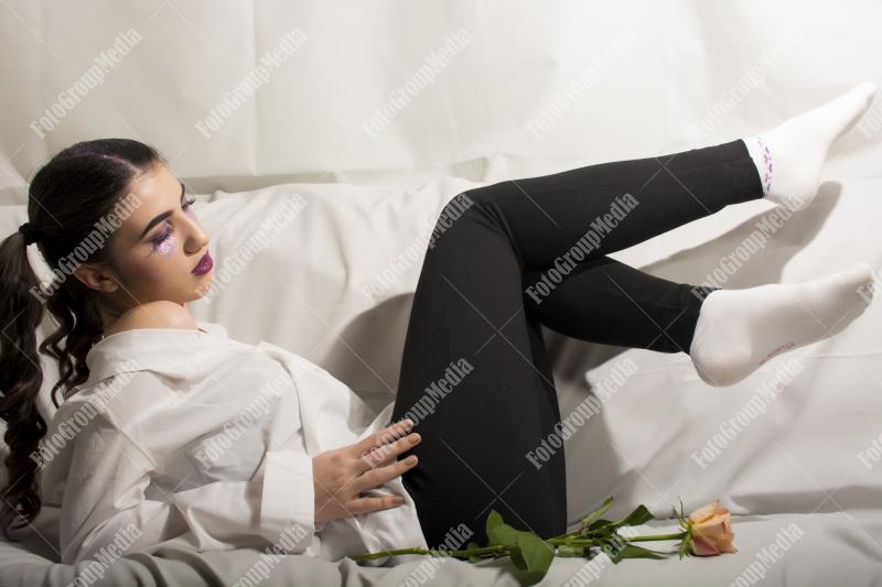Young girl dressed in shirt and black jeans sitting on couch