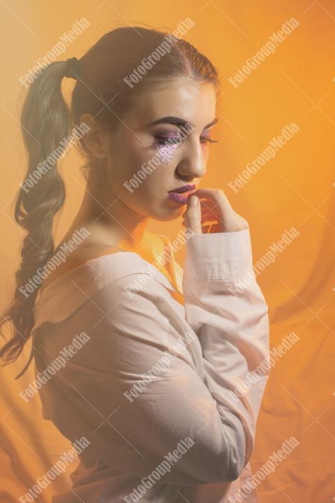 Young girl with two pony tails and artistic make up on yellow background