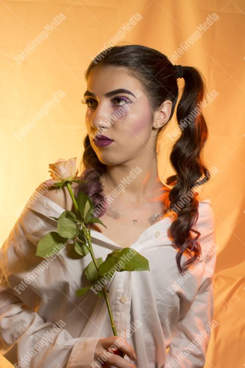 Young girl with artistic make up and yellow rose