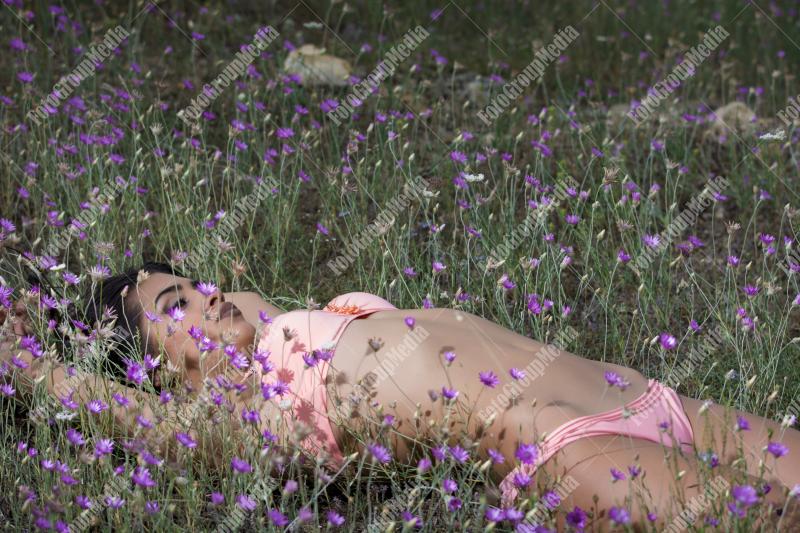 Brunette young girl posing outdoor in a field of wild flowers