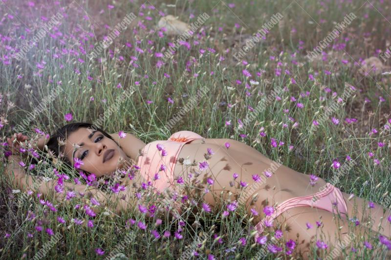 Brunette young girl posing outdoor in a field of wild flowers