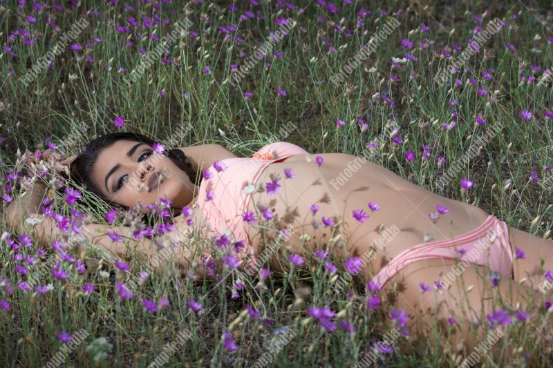 Brunette young girl posing outdoor in a field of wild flowers