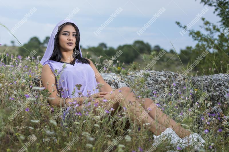Portrait of a young brunette girl in a field of wild flowers