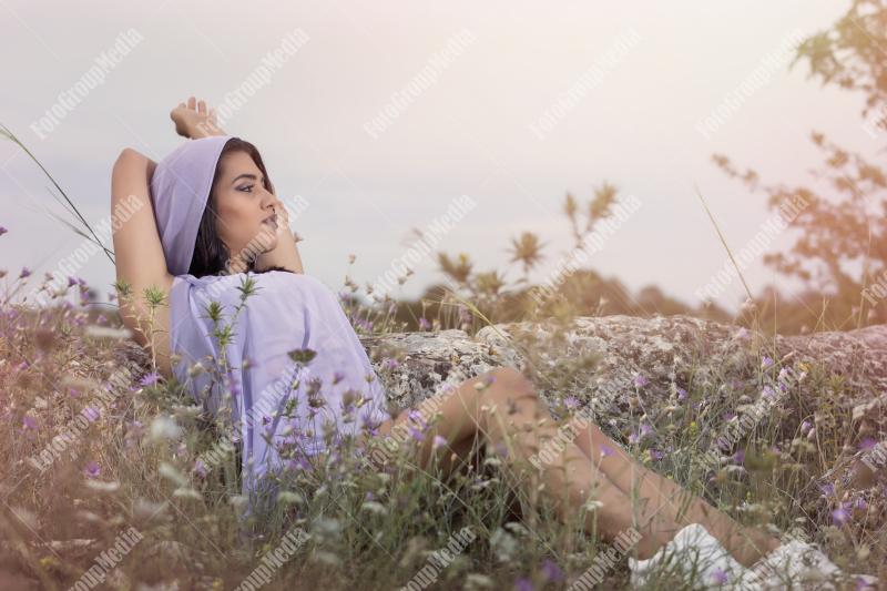 Portrait of a young brunette girl in a field of wild flowers
