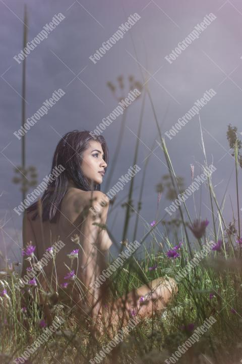 Brunette young girl posing outdoor in a field of wild flowers