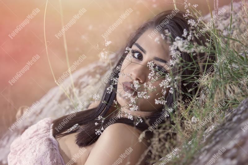 Portrait of a young brunette girl in a field of wild flowers