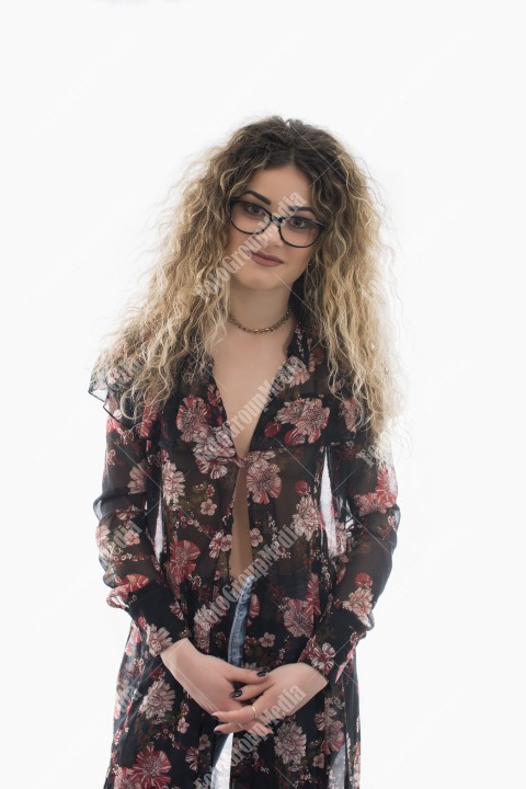 Woman with curly hair and floral dress posing on white background