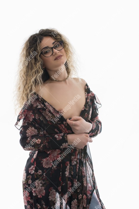 Woman with curly hair and floral dress posing on white background