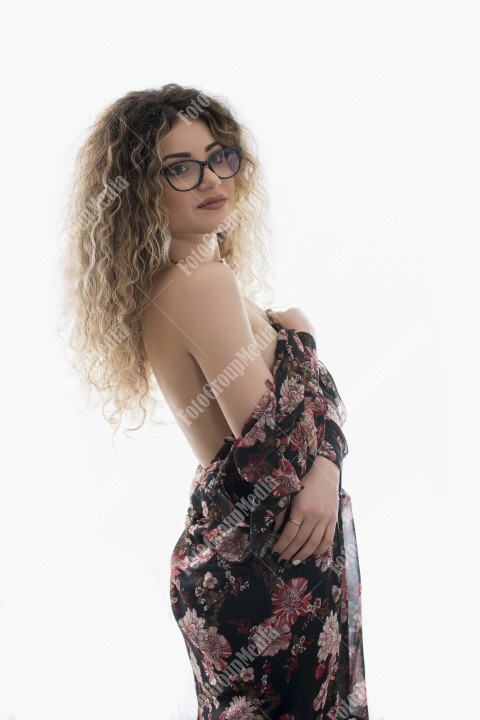 Woman with curly hair and floral dress posing on white background