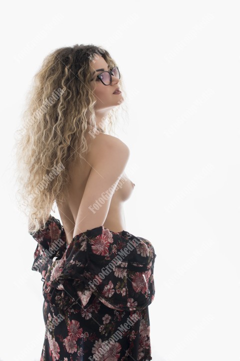 Woman with curly hair and floral dress posing on white background