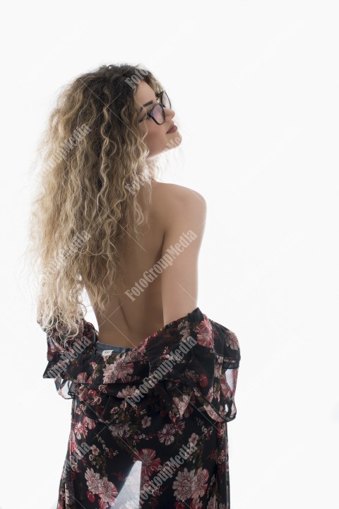 Woman with curly hair and floral dress posing on white background