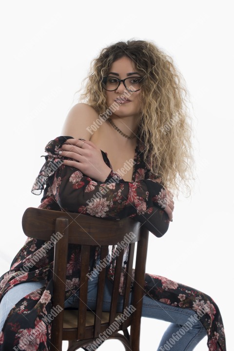 Woman with curly hair and floral dress posing on white background