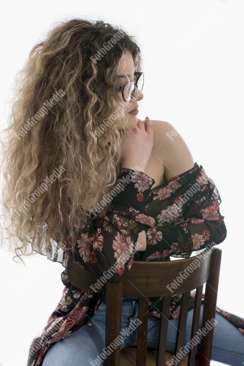Woman with curly hair and floral dress posing on white background