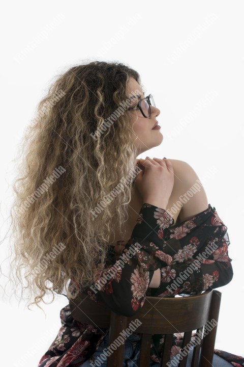 Woman with curly hair and floral dress posing on white background