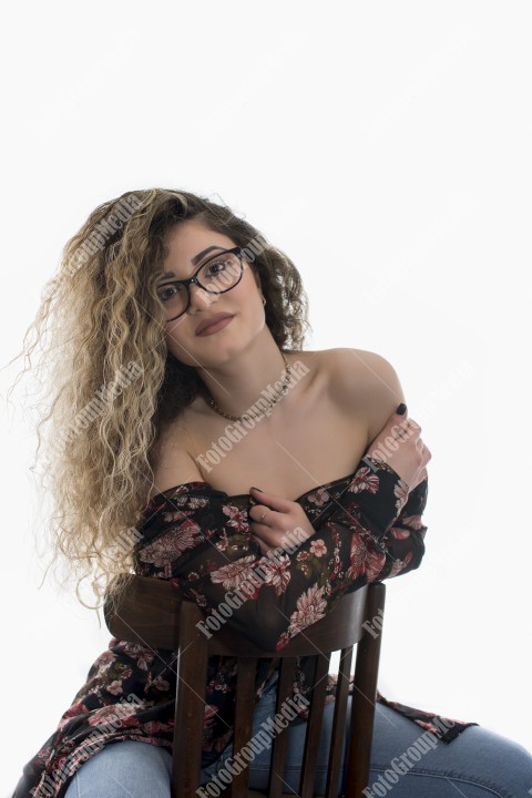 Woman with curly hair and floral dress posing on white background
