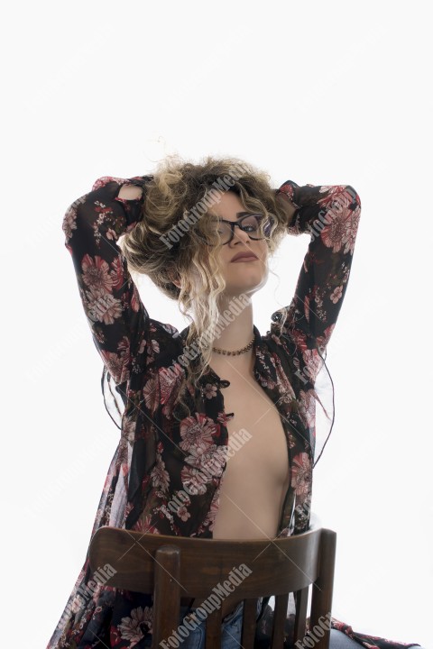Woman with curly hair and floral dress posing on white background