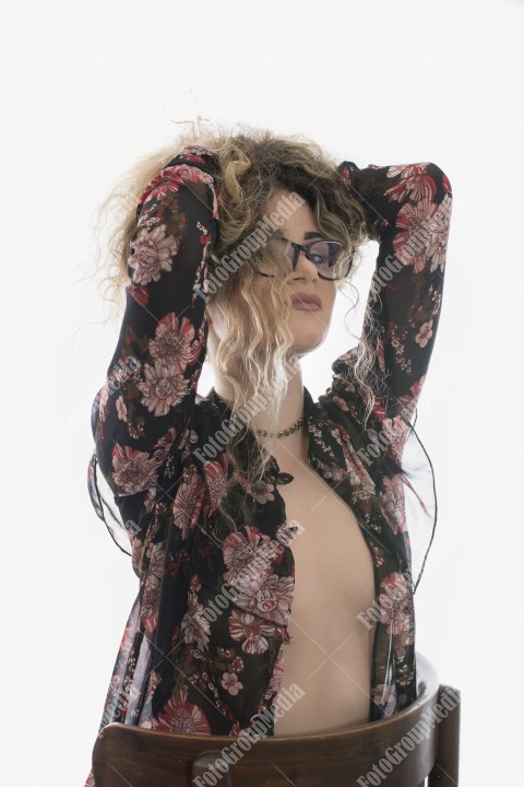 Woman with curly hair and floral dress posing on white background