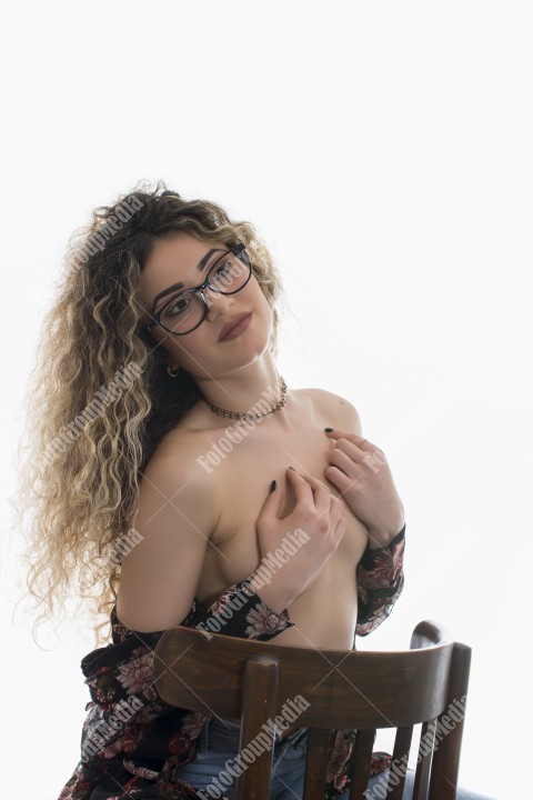 Woman with curly hair and floral dress posing on white background
