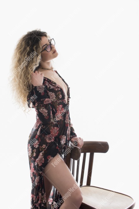 Woman with curly hair and floral dress posing on white background