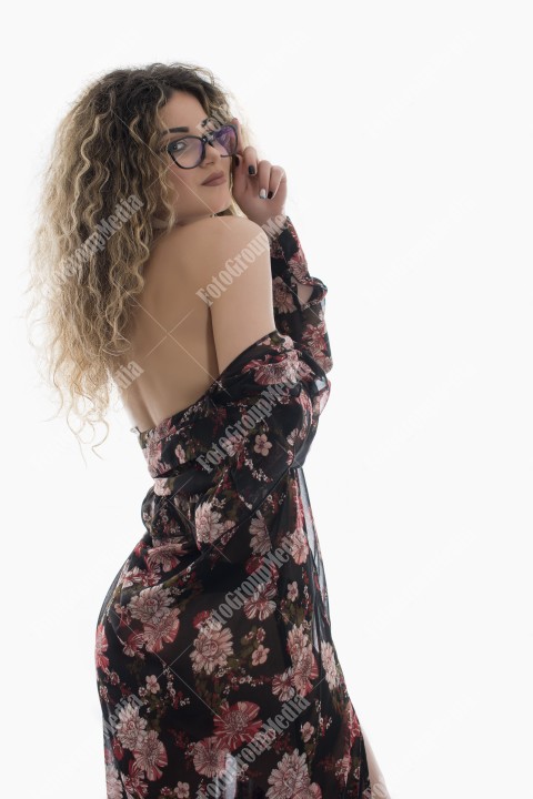 Woman with curly hair and floral dress posing on white background