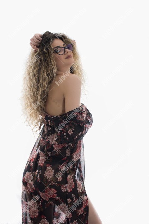Woman with curly hair and floral dress posing on white background