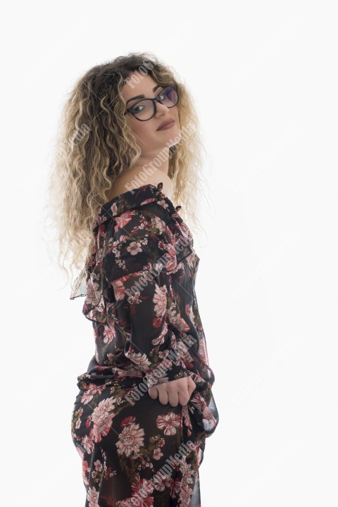 Woman with curly hair and floral dress posing on white background