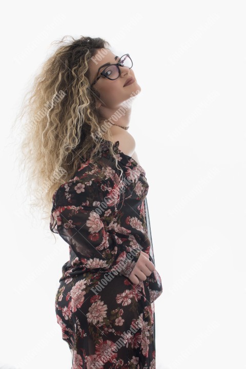 Woman with curly hair and floral dress posing on white background