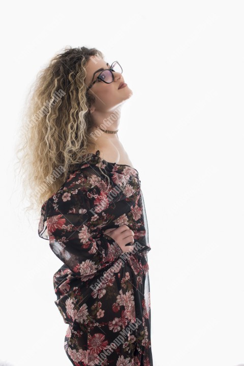 Woman with curly hair and floral dress posing on white background