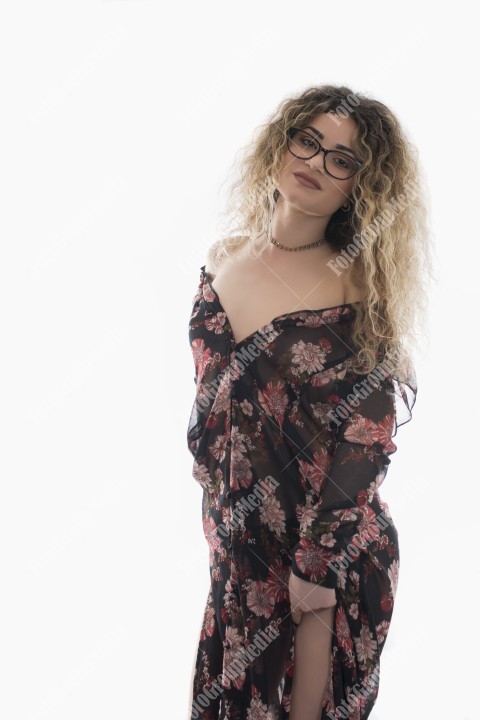 Woman with curly hair and floral dress posing on white background