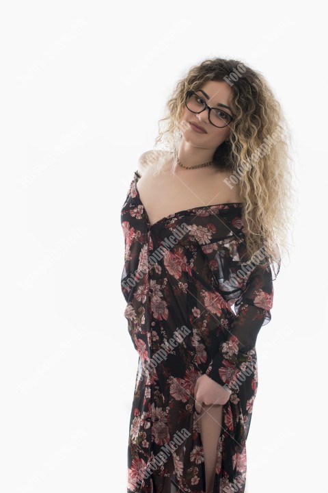 Woman with curly hair and floral dress posing on white background