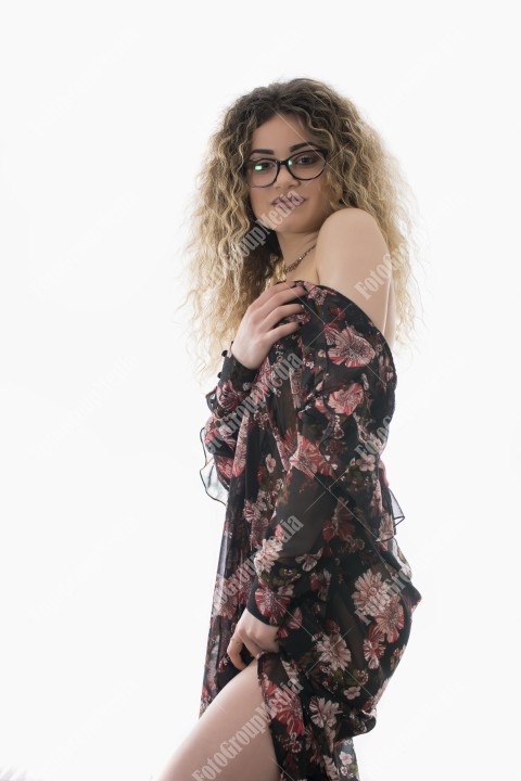 Woman with curly hair and floral dress posing on white background