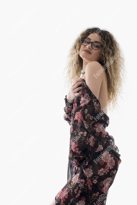 Woman with curly hair and floral dress posing on white background