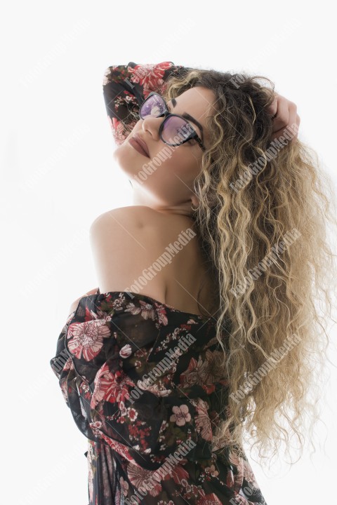 Woman with curly hair and floral dress posing on white background