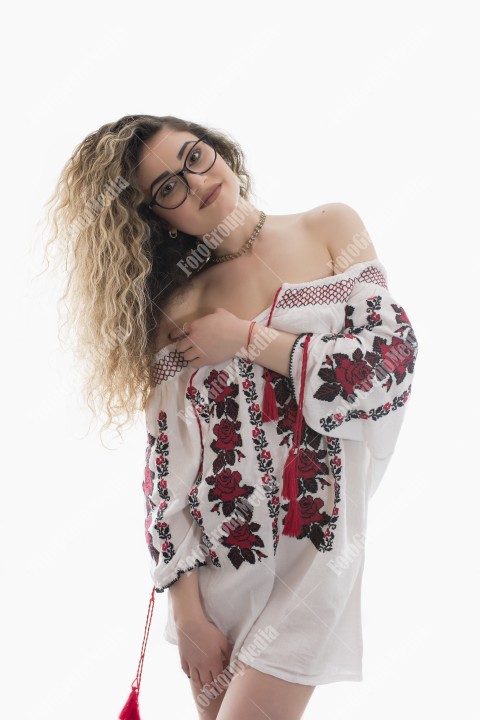 Woman with curly hair and white dress with red flowers posing on white background