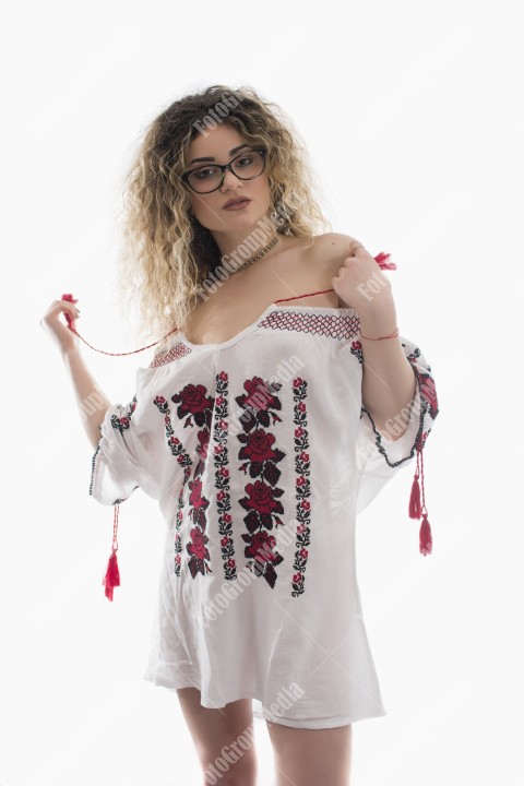 Woman with curly hair and white dress with red flowers posing on white background